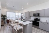 Located in American Fork, Utah, this thoughtfully designed one-bedroom, two-bathroom residence offers an efficient and modern single-floor layout. Light wood-look flooring flows throughout, creating a clean and cohesive aesthetic across the space.

The open-concept kitchen and living area serves as the heart of the home. The kitchen is outfitted with stainless steel appliances, including a full-size refrigerator, electric range, and over-the-range microwave. Taupe-toned flat-front cabinetry with matte black hardware pairs with crisp white countertops, while a central island with seating provides additional prep and dining space. Recessed lighting brightens the area overhead.

The living room is filled with natural light from a sliding glass door that opens to a private balcony, offering open views of the surrounding American Fork area. The bright, airy ambiance makes the space feel welcoming and comfortable.

The generously sized primary bedroom features recessed lighting, a ceiling fan, and a window with outdoor views. It connects to a dedicated closet with built-in shelving. Both bathrooms are clean and functional, with white cabinetry, a full tub-shower combination, and light flooring consistent with the rest of the home. The overall design balances modern finishes with a warm, livable atmosphere.