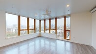 Located in Portland's vibrant Northwest district, this three-bedroom, three-bathroom residence offers a thoughtfully designed single-level layout. The living room is a standout space, featuring wrap-around floor-to-ceiling windows with warm wood framing that flood the room with natural light and frame panoramic views of the Portland skyline and surrounding neighborhoods. A ceiling fan adds a functional touch to this bright, airy space, which is finished with light wood-look flooring found throughout the home.

Each bedroom is well-proportioned and includes windows with city views. The primary bedroom benefits from large corner windows, while additional bedrooms feature sliding closet systems and clean, minimalist design. The bathrooms are finished with modern fixtures, including a full tub-shower combination, tile flooring in slate tones, and vanities with undermount sinks, quartz-style countertops, and wood-grain cabinetry accented by large mirrors.

A dedicated laundry area houses a stacked Bosch washer and dryer unit, adding everyday convenience. Hallways connect each space efficiently, maintaining an open and organized flow throughout. The home's clean white walls, recessed lighting, and consistent flooring create a cohesive, contemporary ambiance well-suited for urban living.