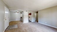 Located at 6006 E 126th St in Grandview, Missouri, this single-floor unit offers a practical and well-organized layout designed for comfortable everyday living. The open living area is finished with neutral-toned carpet and painted in soft gray tones throughout, creating a cohesive and understated ambiance. A ceiling fan overhead adds functional comfort, while a sliding glass door leads to a private balcony, allowing natural light to fill the space and providing outdoor views of the surrounding area.

The galley-style kitchen is a standout feature, lined on both sides with rich cherry-toned cabinetry and dark laminate countertops. White appliances, including a refrigerator, range, and dishwasher, are neatly integrated, and wood-look flooring runs the length of the kitchen. A peninsula counter connects the kitchen to the living space, offering additional workspace or casual seating.

The bedrooms are carpeted and finished in the same neutral palette, each offering closet access. One bedroom includes a structural beam detail and a window for natural light. The bathroom features a full soaking tub and shower combination with built-in wall shelving. Overall, the unit provides a clean, move-in-ready environment with a straightforward, efficient floor plan.