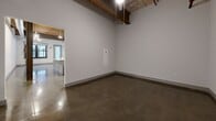 This single-floor unit at 4147 E Main Street Ext in Spartanburg, SC offers a distinctive industrial-loft aesthetic defined by soaring ceilings with exposed wooden beams, visible ductwork, and polished concrete floors that run throughout the space. The open-concept living area benefits from tall ceilings and a ceiling fan, creating an airy, spacious feel. A large window admits natural light, while a glass-panel entry door adds to the bright, modern atmosphere.

The kitchen is a standout feature, equipped with sleek gray cabinetry, granite countertops, a white subway tile backsplash, and a full suite of stainless steel appliances including a refrigerator, range, microwave, and dishwasher. A central island with a granite surface provides additional prep space and casual seating potential.

The bathroom is cleanly finished with white subway tile surrounding a full tub-shower combination, gray cabinetry, and polished concrete flooring that complements the rest of the unit. A dedicated laundry area includes a full-size washer and dryer with overhead wire shelving for added storage.

Overall, the space combines raw architectural character with modern finishes, resulting in a functional and visually compelling interior.