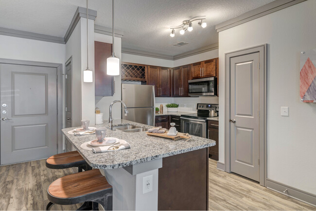 Modern kitchen with wood cabinetry, white tile backsplash, granite countertops, stainless steel appliances, and hard-surface flooring - Avalon Mooresville