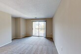 Located at 1900 Windsor Hill Dr in Matthews, NC, this single-floor, one-bedroom, one-bathroom residence offers a practical and comfortable layout. The combined living and dining area forms the heart of the home, with soft carpeting underfoot, neutral warm-toned walls, and a textured ceiling that adds character. A sliding glass door fills the living space with natural light and provides direct access to a private patio with outdoor views of surrounding greenery. The dining area is defined by wood-look flooring and a pendant light overhead, with a pass-through window connecting seamlessly to the kitchen. The kitchen is well-equipped with warm wood cabinetry offering generous storage, laminate countertops, a double-basin sink, and black appliances including a range, over-the-range microwave, dishwasher, and refrigerator. The bedroom is a comfortable retreat featuring plush carpeting, a natural window view, and a closet with louvered bifold doors. The unit also includes three closets total for ample storage, a full bathroom, and a dedicated laundry area. The overall aesthetic is clean and functional, making efficient use of the available space throughout.
