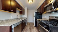 This single-floor residence offers a thoughtfully designed layout that balances functionality and comfort throughout its living spaces. The galley-style kitchen serves as a standout feature, showcasing rich dark espresso cabinetry, granite-look countertops, and a full suite of stainless steel appliances including a gas range, dishwasher, refrigerator, and built-in microwave. Light wood-look luxury vinyl plank flooring runs throughout the main living and kitchen areas, creating a cohesive and easy-to-maintain foundation. Natural light streams into the dining area through wide windows fitted with horizontal blinds, brightening the open space adjacent to the kitchen. The living room is generously sized, with the same warm flooring and neutral wall tones, providing a versatile canvas for various furniture arrangements. The bedroom is finished with plush carpet and features a ceiling fan with lighting, along with a window that invites natural light. The bathroom is clean and functional, featuring tile flooring, a full soaking tub with a tiled surround, and a dark-cabinetry vanity topped with granite-look counters. Throughout the unit, consistent finishes and a neutral color palette create a unified, move-in-ready atmosphere.