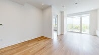 Located at 2855 Ch Bates in Montréal, this well-designed 2-bedroom, 2-bathroom unit offers a thoughtful layout across a single floor. Light hardwood flooring flows throughout the living areas, creating a warm, cohesive aesthetic that complements the clean white walls and recessed lighting.

The open-concept kitchen and living area serves as the heart of the unit. The kitchen features a large central island with an undermount sink, white cabinetry paired with warm wood upper cabinets, stainless steel appliances including a refrigerator and range, and a bright white backsplash. An in-unit stacked washer and dryer is conveniently tucked nearby.

The living area extends toward a sliding glass door that opens to a private balcony, bringing in generous natural light and outdoor views of surrounding greenery. A wall-mounted split heating and cooling unit provides year-round climate control.

Both bedrooms are bright and airy, with large windows framing views of the treetops and ample space for furnishings. Built-in closet storage is present in the primary bedroom area.

The two bathrooms are finished with a modern, minimalist palette of neutral tiles and clean white surfaces. A floating wood-toned vanity with a mirrored medicine cabinet and an oversized glass-enclosed walk-in shower highlight the refined design of the main bathroom.