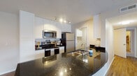 Located at 200 Gallery Dr in Marysville, Ohio, this single-floor residence offers a well-designed layout with a cohesive blend of modern finishes and functional living spaces. The kitchen is a standout feature, showcasing dark granite countertops, white shaker-style cabinetry extending to the ceiling, stainless steel appliances including a range, microwave, and refrigerator, and a peninsula with a built-in sink that opens to the living area. Track lighting illuminates the workspace, while wood-look flooring runs throughout the kitchen and living spaces. The open living area is generously sized, bathed in natural light from multiple windows, and features a ceiling fan and the same warm wood-look flooring. The bedrooms offer plush carpeting, neutral walls, and windows that bring in additional natural light, creating comfortable and restful retreats. The bathrooms are finished with white vanities, large mirrors with overhead lighting, and wood-look flooring, providing a clean and contemporary aesthetic. The tub/shower combinations are accented with crisp white curtains. Throughout the residence, textured ceilings and neutral warm tones create a consistent, welcoming ambiance suited to a variety of interior styles.