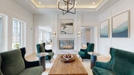 This thoughtfully designed single-floor amenity space blends upscale aesthetics with versatile functionality across several distinct areas. The entry lobby sets an impressive tone with exposed wood beam ceilings, a statement pendant light, and light hardwood flooring accented by inlaid marble tile borders. Marble-topped round tables and leather chairs invite casual gatherings near large glass doors that flood the space with natural light and views of the outdoors.

A central lounge features a floor-to-ceiling marble fireplace flanked by emerald green velvet armchairs, a tray ceiling with a geometric chandelier, and curated abstract artwork, creating a refined yet welcoming atmosphere. Adjacent is a relaxed recreation lounge with a coffered ceiling draped in industrial pendant lighting, a billiards table, and eclectic wall décor that adds a spirited, social character.

The private dining room accommodates large groups around a solid wood communal table beneath dual ring chandeliers, complemented by dark cabinetry, a built-in media display, and a curated gallery wall. The catering kitchen is outfitted with a professional-grade range, stainless steel appliances, white quartz countertops, and glossy subway tile backsplash, offering full culinary capability. Light hardwood flooring flows consistently throughout, unifying the space with warmth and elegance.