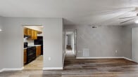 Located at 700 N Spence Avenue in Goldsboro, North Carolina, this single-floor unit offers a well-organized layout designed for comfortable everyday living. Throughout the home, durable wood-look vinyl plank flooring provides a cohesive and modern aesthetic, complemented by neutral gray walls and crisp white baseboards.

The open living and dining area is bright and welcoming, featuring a ceiling fan with a light fixture, a stylish pendant light, and a textured ceiling. The space flows naturally toward the galley-style kitchen, which is equipped with warm oak cabinetry, light speckled countertops, black appliances including a range and refrigerator, and a stainless steel sink — offering ample storage and workspace for cooking.

A central hallway connects the main living areas to the private bedrooms. Each bedroom features a ceiling fan, a textured ceiling, and generous closet space, with at least one room showcasing a built-in organizer system with shelving and hanging rods. Natural light filters in through windows, adding warmth to these well-proportioned rooms.

The bathroom is neatly appointed with a wood-toned vanity, solid-surface countertop, a mirrored medicine cabinet with louvered doors, and a full tub and shower enclosure with built-in shelving. The overall design presents a clean, functional, and move-in-ready living environment.