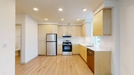 Located in Tigard, Oregon, this two-bedroom, one-bathroom home offers a thoughtfully designed single-floor layout with a clean, modern aesthetic. Light wood-tone flooring flows consistently throughout the space, complementing the crisp white walls and creating a bright, cohesive feel.

The open kitchen and living area serves as the heart of the home. The kitchen is well-appointed with light wood cabinetry extending to the ceiling for generous storage, stainless steel appliances including a refrigerator, electric range, and dishwasher, and a white countertop with an undermount sink positioned near a window for natural light. Recessed ceiling lighting illuminates the space efficiently.

Both bedrooms are comfortably sized with the same warm wood flooring, white walls, and ceiling fans. The primary bedroom offers a modest but functional footprint. The second bedroom features a tall window that brings in natural light and views of greenery outside. Each bedroom benefits from access to a dedicated closet.

The hallway connects the bedrooms efficiently, featuring a sliding barn-style closet door and clean sightlines. The full bathroom includes a soaking tub with an overhead shower, chrome fixtures, and a vanity with wood cabinetry, maintaining the home's consistent modern style. Overall, the space presents a clean, move-in-ready environment with practical, contemporary finishes.