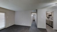 This single-floor residence in DeSoto offers a clean, functional layout designed for comfortable everyday living. The interior is finished with dark hardwood-style flooring that extends throughout the main living area and hallway, providing a cohesive and grounded aesthetic. Neutral, light-toned walls complement the flooring and contribute to a bright, open atmosphere. The textured ceiling adds a classic touch found throughout the unit. A central hallway connects the main living space to the private areas of the home, with overhead lighting guiding the way to rooms at the rear. Ceiling-mounted HVAC vents are integrated throughout, ensuring consistent climate control. The open living area offers ample wall space and a versatile layout, making it well-suited for a variety of furniture arrangements. The overall design is simple and practical, with an emphasis on clean lines and neutral finishes that provide a blank canvas for personalization. This single-story layout ensures ease of movement throughout the space, making it accessible and efficient for day-to-day use.