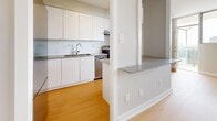 Located at 99 West Lodge Avenue in Toronto's vibrant Parkdale neighbourhood, this two-bedroom, one-bathroom unit offers a clean, modern aesthetic throughout. Light wood laminate flooring runs continuously across the open-concept living space, creating a warm and cohesive feel.

The kitchen is thoughtfully designed with sleek white cabinetry extending floor to ceiling, a white subway tile backsplash, stainless steel appliances, and a built-in countertop ledge that serves as a convenient breakfast bar or pass-through to the living area. The living room is bathed in natural light from floor-to-ceiling windows and opens directly onto a private balcony with open city views.

The primary bedroom is generously proportioned and features large windows with a baseboard heating unit below, providing ample natural light and comfort. The second bedroom is well-sized with its own window and easy access to the shared spaces. A dedicated closet with sliding doors adds practical storage. The full bathroom features a clean white tiled tub-shower surround with chrome fixtures, maintaining the unit's consistent neutral palette.

Soft grey walls, white trim, and recessed lighting complete the refined, contemporary look throughout this well-appointed Toronto residence.