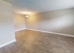 Located at 401 Rosary Rd NE in Largo, Florida, this compact single-room space spans 290 square feet across one floor. The interior presents a clean, functional layout finished with warm wood-look plank flooring that runs throughout the entire space, offering both durability and visual appeal.

The walls are painted in a neutral greige tone, complemented by crisp white baseboards that frame the perimeter of the room. A textured popcorn ceiling adds a classic touch overhead, with a simple pendant light fixture providing overhead illumination. A smoke detector is also ceiling-mounted, meeting safety standards.

Natural light enters through a window fitted with horizontal blinds, brightening the open interior and offering a view of the surrounding outdoor greenery. The entry is secured by a solid white door with a brushed nickel lever-style handle and deadbolt lock, providing a secure and accessible entryway.

Multiple electrical outlets are distributed along the walls, offering practical utility throughout the space. The room's open, unfurnished layout makes it highly adaptable for a variety of uses. Overall, the space presents a well-maintained, move-in-ready interior with consistent finishes that create a cohesive and functional environment.
