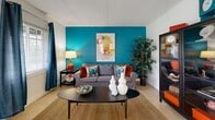 Located at 5701 6th Ave N in Saint Petersburg, FL, this one-bedroom, one-bathroom residence offers a thoughtfully designed single-floor layout with a cohesive, colorful interior aesthetic. The living room serves as the heart of the home, featuring a bold teal accent wall, light tile flooring, and a window that brings in natural light with outdoor views — creating a lively yet comfortable atmosphere. A dedicated dining area adjacent to the living space offers an intimate setting, accented by contemporary wall art and track lighting. The kitchen is efficiently arranged with white cabinetry, a tile backsplash, light countertops, and full appliances including a range and refrigerator, with a window providing additional natural light. The bedroom features wood-style flooring, a striking red accent wall, and a window dressed with sheer curtains, offering a warm and restful retreat. The full bathroom includes a tub-shower combination with tile surround, a white vanity with stone-style countertop, and tile flooring. A hallway connects the rooms, contributing to the functional flow of the space. Throughout, the home maintains a cohesive, vibrant color palette reflective of its Florida coastal setting.