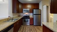 Located at 4133 Arbor Dr in Shrewsbury, MA, this single-floor unit offers a thoughtfully arranged layout visible across its open-concept living and dining areas. Rich, dark hardwood-style flooring flows through the main living spaces, complemented by neutral beige walls and textured ceilings throughout.

The kitchen is well-appointed with rich dark cabinetry, granite-style countertops, and a full suite of stainless steel appliances, including a gas range, over-the-range microwave, refrigerator, and dishwasher. A breakfast bar connects the kitchen to the main living area, which opens toward a sliding glass door providing natural light and outdoor views.

A central hallway leads to the private sleeping areas, each finished with plush carpeting. One bedroom features a large window overlooking greenery, while another includes a spacious walk-in closet with wire shelving. Two full bathrooms serve the unit: one with a white vanity and tub-shower combination, and another with grab bars and hardwood-style flooring. The overall ambiance is clean, neutral, and move-in ready.