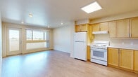 Located at 150 E Avenue R in Palmdale, CA, this 2-bedroom, 1-bathroom unit offers a thoughtfully laid-out single-floor plan with a clean, modern aesthetic. Light wood-tone flooring runs throughout the entire space, creating a warm and cohesive feel. The combined kitchen and living area serves as the heart of the unit, featuring a well-appointed kitchen with light maple cabinetry, white appliances including a refrigerator, electric range, and dishwasher, and a skylight that floods the space with natural light. The open living area connects seamlessly, with a glass door providing additional outdoor light and access. Both bedrooms are comfortably sized with large sliding windows that invite natural light and offer views of the surrounding neighborhood. The primary bedroom includes a built-in closet with sliding doors, providing ample storage. A hallway connects the bedrooms to the full bathroom, which features a soaking tub and shower combination, grab bars, and matching wood-tone flooring. The unit's neutral color palette and recessed lighting throughout contribute to a bright, airy ambiance that is both functional and inviting.
