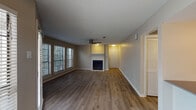 This single-floor space offers a thoughtfully designed layout that balances comfort and functionality. The living area serves as the heart of the home, featuring warm wood-look laminate flooring, a classic fireplace with a clean white surround, and a ceiling fan overhead. A large multi-panel window floods the room with natural light and provides views of surrounding greenery, creating an inviting and airy atmosphere. A textured ceiling adds a traditional touch throughout.

The open-concept design connects the living area to the kitchen, which is accessible via a pass-through counter. The kitchen features white cabinetry, a sink, and stainless steel appliances, offering a practical and clean aesthetic. A glass-panel door leads to an exterior entry, further enhancing natural light in the space.

The hallway connects the living areas to the private rooms, with light-toned laminate flooring continuing seamlessly throughout. The bedroom is well-proportioned, featuring a ceiling fan, a window with blinds, and a neutral color palette that creates a calm retreat.

The bathroom showcases a modern floating vanity with warm wood-toned cabinetry, a white countertop sink, and a framed mirror illuminated by stylish vanity lighting — a refined detail that elevates the overall design. The space is finished with consistent neutral wall tones and clean white trim throughout.