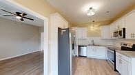 Located at 1019 Kingscote Dr in Fayetteville, NC, this two-story home offers a well-designed layout with a clean, contemporary aesthetic throughout. The kitchen is equipped with white shaker-style cabinetry extending to the ceiling for ample storage, granite countertops, a white subway tile backsplash, stainless steel appliances including a refrigerator and dishwasher, and a double sink. Light wood-look flooring carries through the kitchen and main living areas, creating a cohesive and bright atmosphere. The dining area adjacent to the kitchen features vaulted ceilings, a stylish multi-arm chandelier, and sliding glass doors that open to a fenced backyard, filling the space with natural light. The living room is highlighted by a built-in fireplace framed with a white mantel, flanked by two windows, and finished with a ceiling fan overhead. Bedrooms are carpeted for comfort and include ceiling fans and generous natural light from well-placed windows. At least one bedroom benefits from a spacious walk-in closet with wire shelving. The bathrooms feature tub-shower combinations with brushed nickel fixtures and clean, neutral finishes. Overall, the home presents a fresh, move-in-ready condition with neutral tones and modern touches throughout both floors.