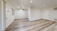 Located at 970 S Menlo Ave in Los Angeles, CA, this 1-bedroom, 1-bathroom unit offers a clean, modern interior across a single floor. Light wood-style flooring runs throughout the living spaces, creating a cohesive and contemporary feel. The open living room is generously sized, featuring recessed lighting, a ceiling fan, and large vertical-blind windows that allow natural light to fill the space. A dedicated kitchen area is outfitted with crisp white shaker cabinets, dark countertops, a classic subway tile backsplash, a stainless steel sink, and a stainless steel gas range with overhead ventilation. The bedroom offers a comfortable footprint, complete with a ceiling fan, a window with natural light, and a sliding mirrored closet door that adds depth to the room. The bathroom is finished in a clean, all-white palette with tile flooring, a glass-enclosed tub-shower combination, a white vanity with countertop sink, and a medicine cabinet mirror. A hallway connects the main living areas to the private spaces, maintaining a functional and efficient layout throughout. The overall ambiance is bright, fresh, and move-in ready.