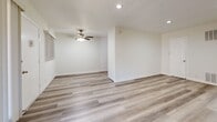 Located at 970 S Menlo Ave in Los Angeles, CA, this 1-bedroom, 1-bathroom unit offers a clean, modern interior across a single floor. Light wood-style flooring runs throughout the living spaces, creating a cohesive and contemporary feel. The open living room is generously sized, featuring recessed lighting, a ceiling fan, and large vertical-blind windows that allow natural light to fill the space. A dedicated kitchen area is outfitted with crisp white shaker cabinets, dark countertops, a classic subway tile backsplash, a stainless steel sink, and a stainless steel gas range with overhead ventilation. The bedroom offers a comfortable footprint, complete with a ceiling fan, a window with natural light, and a sliding mirrored closet door that adds depth to the room. The bathroom is finished in a clean, all-white palette with tile flooring, a glass-enclosed tub-shower combination, a white vanity with countertop sink, and a medicine cabinet mirror. A hallway connects the main living areas to the private spaces, maintaining a functional and efficient layout throughout. The overall ambiance is bright, fresh, and move-in ready.