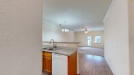 This single-story, 2-bedroom, 1-bathroom home offers a practical and comfortable layout across a well-utilized footprint. The open-concept design connects the kitchen and living room, creating a cohesive and functional shared space. The kitchen is equipped with warm honey-toned wood cabinetry, granite-style countertops, a tile backsplash, and white appliances including an electric range, built-in microwave, dishwasher, and refrigerator. A peninsula with a double stainless steel sink serves as a natural divider between the kitchen and living area, allowing for easy interaction between spaces. The living room features hardwood-style flooring, crown molding, a ceiling fan, and a window that allows natural light to fill the room.

Both bedrooms are carpeted and finished with neutral walls and clean white trim, offering a calm and versatile environment. The primary bedroom is notably spacious, providing ample room for furniture arrangements. The single full bathroom includes a wood-toned vanity with a white countertop, a tub-shower combination, and hardwood-style flooring. A hallway connects the private areas of the home, completing the efficient and straightforward floor plan.