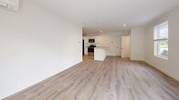 This well-appointed single-floor residence offers a clean, modern aesthetic throughout, with a thoughtful layout that maximizes both comfort and functionality. The open-concept living and dining area is anchored by light-toned hardwood-style flooring and flooded with natural light through multiple windows fitted with blinds, along with a sliding glass door that opens to an outdoor view of mature trees — creating a bright, airy atmosphere. A wall-mounted mini-split unit provides efficient climate control.

The kitchen flows seamlessly from the living space and features white cabinetry, stone-toned countertops, a central peninsula, and a full suite of stainless steel appliances including a refrigerator, electric range, over-the-range microwave, and sink — making it both practical and visually cohesive.

The bedrooms are carpeted for comfort, each offering a quiet retreat with baseboard heating and natural light. The primary bedroom includes a set of double-door closets. The full bathroom is finished in crisp white tones, featuring a single-vanity with brushed nickel hardware, a large mirror, a tub-shower combination, wood-look tile flooring, and access to an additional walk-in closet with built-in shelving. Throughout, the neutral color palette and clean finishes create a welcoming, move-in-ready environment.