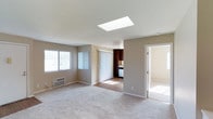 Located at 6675 Jaffe Ct in San Diego, this single-floor residence offers a thoughtfully designed layout with a clean, neutral aesthetic throughout. The spacious living area is a standout, featuring a large skylight that floods the room with natural light, complemented by plush carpeting and vertical blinds that frame the windows. A wall-mounted A/C unit provides climate control, while an open sightline connects the living space directly to the kitchen.

The kitchen is well-equipped with rich, dark wood cabinetry extending to the ceiling for ample storage, light stone countertops, and a full suite of stainless steel appliances including a range, built-in microwave, dishwasher, and refrigerator. Wood-look flooring anchors the kitchen and dining area, creating a warm contrast to the surrounding neutral walls.

The bedrooms are carpeted and bright, each featuring windows with vertical blinds that allow for natural light and privacy. The two bathrooms are consistently finished with dark wood vanities, stone-toned countertops, large wall mirrors, and tile flooring. One bathroom includes a combination tub and shower, while the second features a walk-in shower stall, both outfitted with modern brushed nickel fixtures. The overall ambiance is clean, functional, and move-in ready.