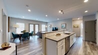 Located at 22 Washington Ave in Sandy Hook, Connecticut, this single-floor residence showcases a thoughtfully designed open-concept layout that seamlessly integrates the kitchen, dining, and living areas into one cohesive and welcoming space. The interior is finished with wide-plank hardwood flooring throughout, recessed lighting, and a neutral gray-toned color palette that lends a clean, contemporary feel.

The kitchen is a standout feature, equipped with white shaker cabinetry, quartz countertops with a dark contrasting edge, a tile backsplash, and a full suite of stainless steel appliances including a refrigerator, range, and microwave. A generously sized island with bar seating provides both additional prep space and casual dining options.

The adjacent living room is bright and welcoming, with multiple windows and French doors that invite natural light and offer views of the surrounding landscape. The dining area, positioned near the French doors, provides an intimate setting accented by large-scale wall art.

The bedrooms are well-appointed, each offering closet storage — including a dedicated walk-in closet in the primary bedroom. The bathroom is elegantly finished with light tile flooring, dark wood vanity cabinetry, a white quartz countertop, and a glass-enclosed walk-in shower with floor-to-ceiling tile surround.