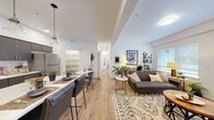 This thoughtfully designed 2-bedroom, 2-bathroom residence offers a functional and modern open-concept layout across a single floor. Light wood flooring flows throughout, creating a cohesive and airy feel from room to room.

The kitchen is a standout feature, showcasing dark wood cabinetry with gold hardware, a white subway tile backsplash, stainless steel appliances, and a central island with bar seating — ideal for both meal prep and casual dining. A dedicated dining area with a round table sits adjacent, completing the eat-in space.

The open living room benefits from natural light streaming through large windows and a glass exterior door, which adds a bright, welcoming ambiance. The space connects seamlessly to the kitchen and hallway beyond.

Both bedrooms are comfortably sized, with the primary bedroom featuring generous proportions, large windows with outdoor views, and ample closet space. The second bedroom is equally well-lit and includes a closet. Each bathroom features dark wood vanities with gold-toned hardware, light quartz countertops, and wood-look flooring.

Additional spaces include a hallway, pantry, and dedicated closet for added storage. The clean, neutral palette throughout makes this a versatile and move-in-ready home.