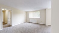 Located at 8508 16th St in Silver Spring, Maryland, this two-bedroom, one-bathroom residence offers a practical and well-organized single-floor layout. The living area is generously sized, featuring neutral-toned carpet flooring, cream-colored walls, and a large window dressed with vertical blinds that invites natural light and provides outdoor views. A pendant light fixture adds a subtle decorative touch near the entryway. The kitchen is equipped with warm oak cabinetry, dark granite-style countertops, light tile flooring, and black appliances including a gas range, dishwasher, and refrigerator — offering a functional cooking space with ample storage. The spacious primary bedroom features plush carpeting, a large window with vertical blinds, a baseboard heating unit, and a textured ceiling. The second bedroom mirrors a similar layout with carpet flooring, natural light, and its own closet with louvered bifold doors. Three closets throughout the unit provide excellent storage capacity. The bathroom includes a tiled shower-tub combo and tile flooring, maintaining a clean and utilitarian design. Throughout the residence, the light, neutral color palette and carpeted floors create a calm, cohesive ambiance suited for comfortable everyday living.