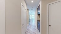 Unit 301 at 410 E 7th Street is a well-appointed third-floor condominium offering 970 square feet of single-level living space in Frederick, MD. The unit features 2 bedrooms, 2 bathrooms, and a thoughtfully designed open-concept layout. The combined kitchen and dining area is a standout, showcasing warm wood cabinetry, stainless steel appliances including a refrigerator, microwave, and range, a subway tile backsplash, and a large center island with quartz-style countertops and pendant lighting. Large windows flood the space with natural light throughout. The primary bedroom spans 150 square feet and features plush carpeting and multiple windows with outdoor views. The second bedroom is equally well-lit with large windows and soft carpet flooring. Both bathrooms are finished with neutral tile, and at least one features a glass-enclosed walk-in shower. Light wood-look flooring runs through the main living areas and hallway, complemented by dark blue built-in cabinetry. The unit also includes an in-unit laundry area, four closets for ample storage, and a private balcony overlooking the surrounding neighborhood and green tree line.