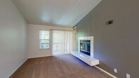 This single-floor residence offers a thoughtfully designed layout that balances comfort and functionality. The living room is a standout space, featuring vaulted ceilings that create an airy, open feel, complemented by a white-tiled fireplace set against a teal accent wall. Large sliding glass doors with vertical blinds flood the room with natural light and provide outdoor views, while plush carpeting adds warmth underfoot.

The open layout connects the living area to the dining space, which is highlighted by an elegant chandelier and wood-look flooring. A pass-through window links the dining area to the kitchen, enhancing the sense of connectivity throughout the home. The galley-style kitchen is efficiently designed with white cabinetry, light countertops, a double sink, and a full suite of appliances including a refrigerator, electric range, microwave, and dishwasher, all set on durable wood-look flooring.

The bedrooms are carpeted and bright, benefiting from natural light through large windows. Vaulted ceilings in the entry area add architectural interest. The bathroom is clean and functional, featuring a full tub-shower combination, wood-look flooring, and a well-lit vanity. Overall, the residence presents a practical and welcoming living environment with consistent finishes throughout.