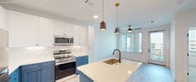 This contemporary 620 square foot apartment in Denver offers a harmonious blend of style and functionality. The space is efficiently designed with one bedroom, one bathroom, and an open-concept living area. The bathroom showcases a modern aesthetic with clean lines, a spacious vanity, and a large mirror, complemented by hexagonal floor tiles that add visual interest.

The kitchen is a standout feature, boasting a striking two-tone color scheme with white upper cabinets and bold blue lower cabinets. Stainless steel appliances, including a refrigerator and built-in microwave, enhance the kitchen's modern appeal. The kitchen island, topped with a light-colored countertop, provides additional workspace and casual seating.

The living areas benefit from wood-look flooring that adds warmth to the space. Large windows in the bedroom and living room flood the apartment with natural light and offer views of the surrounding cityscape. The bedroom, measuring 130 square feet, features plush carpeting and ample space for a comfortable retreat.

Throughout the apartment, recessed lighting and modern ceiling fixtures provide well-distributed illumination. The overall color palette of whites and blues creates a fresh, inviting atmosphere. With its thoughtful design and attention to detail, this apartment offers a desirable urban living experience in the heart of Denver.