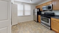 Located at 99 Crater Cir in Petersburg, Virginia, this single-floor residence offers a practical and comfortable layout designed for everyday living. The kitchen serves as a functional centerpiece of the home, featuring warm honey-toned wood cabinetry, dark granite-style countertops, and a full suite of stainless steel appliances including a gas range, over-the-range microwave, refrigerator, and dishwasher. Stone-look tile flooring runs throughout the kitchen, providing durability and easy maintenance. Natural light filters in through multiple windows dressed with white blinds, brightening the space with a clean, neutral aesthetic. The open floor plan, as seen in the overhead layout, connects the kitchen to a spacious living area finished with plush carpeting, creating a warm and inviting atmosphere. The home includes bathrooms featuring full soaking tub and shower combinations with crisp white surrounds and polished chrome fixtures, complemented by tile flooring that adds a refined touch. Throughout the residence, the light-toned walls and consistent finishes contribute to a cohesive and well-maintained interior. This single-level home presents a straightforward, move-in-ready living environment suited for a variety of lifestyles.