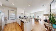 Located at 99 Southport Cir in Brunswick, Georgia, this well-appointed two-story home offers three bedrooms and three bathrooms across two thoughtfully designed floors. The main level welcomes you through a bright, arched hallway adorned with light wood flooring and abundant natural light from strategically placed windows. The open-concept living area seamlessly connects the kitchen, dining room, and living room, creating an inviting space for both everyday living and entertaining. The kitchen is equipped with white shaker cabinetry, granite countertops, a subway tile backsplash, stainless steel appliances, and a central island with a sink and breakfast bar seating. The adjoining living room features soaring ceilings and a ceiling fan, while large windows allow ample natural light to fill the space. The main floor also includes an attached garage, a pantry, and a laundry room with a full-size washer and dryer. Upstairs, the primary bedroom is generously sized and filled with natural light from multiple windows. The additional bedrooms are equally well-lit and comfortable. The bathrooms feature granite vanity countertops, white cabinetry, and clean, bright finishes. With five closets throughout, storage is plentiful. The home sits in a developing Brunswick neighborhood surrounded by mature trees.