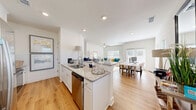 Located at 99 Southport Cir in Brunswick, Georgia, this well-appointed two-story home offers three bedrooms and three bathrooms across two thoughtfully designed floors. The main level welcomes you through a bright, arched hallway adorned with light wood flooring and abundant natural light from strategically placed windows. The open-concept living area seamlessly connects the kitchen, dining room, and living room, creating an inviting space for both everyday living and entertaining. The kitchen is equipped with white shaker cabinetry, granite countertops, a subway tile backsplash, stainless steel appliances, and a central island with a sink and breakfast bar seating. The adjoining living room features soaring ceilings and a ceiling fan, while large windows allow ample natural light to fill the space. The main floor also includes an attached garage, a pantry, and a laundry room with a full-size washer and dryer. Upstairs, the primary bedroom is generously sized and filled with natural light from multiple windows. The additional bedrooms are equally well-lit and comfortable. The bathrooms feature granite vanity countertops, white cabinetry, and clean, bright finishes. With five closets throughout, storage is plentiful. The home sits in a developing Brunswick neighborhood surrounded by mature trees.