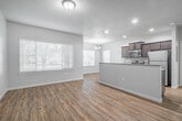 This one-bedroom, one-bathroom residence in Meridian, Idaho offers a thoughtfully designed layout that maximizes functionality and comfort. Wood-look flooring flows consistently throughout the entire space, lending warmth and visual cohesion to every room.

The open-concept kitchen and dining area serves as the heart of the home. The kitchen is outfitted with rich dark-wood cabinetry, granite-look countertops, a tile backsplash, and a full suite of stainless steel appliances, including an electric range, over-the-range microwave, and refrigerator. A peninsula with a built-in sink provides additional counter space and casual seating options. Recessed lighting and a pendant chandelier illuminate the combined kitchen and dining zone.

The living room is generously sized, featuring large windows with blinds that invite abundant natural light and views of the surrounding greenery. The bedroom is a comfortable and private retreat, also benefiting from a natural-light-filled window. Three closets throughout the unit provide ample storage.

The bathroom is clean and efficiently laid out, complete with a full tub-shower combination, toilet, and a vanity with dark wood cabinetry. Additional conveniences include a dedicated laundry area and an outdoor patio, rounding out this practical and inviting residence.