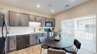 This thoughtfully designed two-story home in Rochester, Minnesota offers a comfortable and contemporary living experience across two well-appointed floors. The main level features an open-concept kitchen and dining area finished with rich dark cabinetry, a white subway tile backsplash, black appliances, and light hardwood-style flooring that carries throughout the home. A sliding door in the kitchen area allows natural light to pour in. The inviting living room is anchored by a sleek linear fireplace framed in white with recessed lighting overhead, creating a warm and modern focal point. A welcoming entry hallway with a built-in bench sets an organized tone from the moment you arrive. Upstairs, the upper level offers generous living space including both bedrooms, two full bathrooms, a loft area, and a convenient in-unit laundry. The primary bedroom features a ceiling fan, sliding door access to an exterior area, and ample natural light. The second bedroom is bright and comfortable with a large window and ceiling fan. Both bathrooms are finished with dark wood vanities, white countertops, and matte black hardware. Multiple closets and hallways ensure abundant storage throughout this well-organized home.