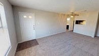This single-floor, one-bedroom, one-bathroom unit offers a functional and straightforward layout designed for comfortable everyday living. The living area is generously proportioned, featuring neutral-toned carpet, light gray walls, a textured ceiling, and a ceiling fan with an integrated light fixture. A front entry door with decorative glass inserts opens directly into this space, which also benefits from a window allowing natural light to filter in. A pass-through window connects the living area to the kitchen, enhancing the open feel between the two spaces.

The galley-style kitchen is efficiently arranged, featuring dark espresso cabinetry on both sides, light-toned countertops, a double stainless steel sink, and a black electric coil range with overhead ventilation. Wood-look flooring runs throughout the kitchen, adding a warm contrast to the darker cabinetry.

The bedroom is a comfortable size, finished with carpet, a ceiling fan with lighting, a window with exterior views, and neutral walls throughout. The full bathroom includes wood-look flooring, a dark vanity with a light countertop, a standard toilet, and a tub-shower combination with tiled surround, offering clean and practical finishes.