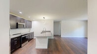 Located in Swiftwater, PA, this two-bedroom, one-bathroom residence offers a well-organized single-floor layout with a clean, modern aesthetic throughout. Rich, dark hardwood flooring flows consistently across every room, providing a warm and cohesive foundation for the entire space.

The kitchen is a standout feature, showcasing dark espresso shaker-style cabinetry, granite countertops, a classic white subway tile backsplash, and stainless steel appliances including a refrigerator, range, and built-in microwave. A large island with an integrated sink and a contemporary pendant light fixture adds both function and style to the space.

The combined kitchen and living area transitions seamlessly, with the living room offering access to the outdoors via a glass-paneled door alongside a large window that frames lush, wooded views. Each bedroom features the same hardwood flooring, neutral wall tones, and windows overlooking the natural surroundings, with the generously sized primary bedroom offering ample room for furnishings. Two closets provide convenient storage throughout the unit.

The bathroom is finished with clean white walls, wood-look flooring, and a white vanity. A dedicated utility room and two closets round out the practical layout. The surrounding landscape features mature trees, contributing to a peaceful, nature-connected setting.
