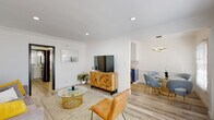 Located in the desirable Los Feliz neighborhood of Los Angeles, this single-floor unit at 1828 N Edgemont St offers a thoughtfully designed, modern interior with a clean, bright aesthetic throughout. Light wood-look flooring flows seamlessly across all living areas, complemented by crisp white walls and crown molding that add a classic architectural touch.

The open-concept living area is warm and welcoming, featuring a wall-mounted split A/C unit, recessed lighting, and a bold black front door. The space transitions naturally into a dedicated dining nook, distinguished by a glass-top round table with gold accents, soft blue chairs, wainscoting detail, and a window that lets in natural light.

The galley-style kitchen is a standout feature, outfitted with navy blue lower cabinets, white upper cabinets, white quartz countertops, a classic subway tile backsplash, stainless steel appliances including a gas range, and a deep double sink with a professional-style faucet.

The bedroom is serene and airy, with multiple windows dressed in white wood blinds allowing ample natural light, light wood flooring, and clean white walls that create a restful atmosphere.

The bathroom is elegantly appointed with dramatic marble-style tile surrounding the soaking tub and shower, a modern floating vanity, and wood-look flooring, offering a spa-like feel. This unit combines contemporary finishes with functional design throughout.
