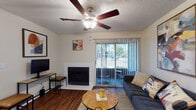 This single-floor, 2-bedroom, 2-bathroom residence in Jacksonville, FL offers a well-organized layout with comfortable living spaces throughout. The living room serves as the heart of the home, centered around a white tile-surround fireplace and anchored by rich hardwood-style flooring. A ceiling fan with a light fixture keeps the space comfortable, while a sliding glass door fitted with vertical blinds opens to an outdoor patio, allowing natural light to flow in and providing views of the surrounding greenery.

The primary bedroom features plush carpeting, a ceiling fan, and a private en-suite bathroom complete with a single-sink vanity, tub-shower combination with white tile surround, and hardwood-style flooring. The second bedroom is equally comfortable, offering carpeted floors, a ceiling fan, a walk-in closet, and a bright window that invites natural light. A second full bathroom mirrors the clean, functional design of the first.

Both bathrooms are finished with white cabinetry, updated fixtures, and tub-shower combinations. Textured ceilings are consistent throughout, and ceiling fans are present in every main room, reflecting the practical design suited to Florida's warm climate. The patio access adds an inviting outdoor extension to this functional and well-appointed residence.