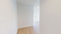 Located on Wilshire Boulevard in the heart of Los Angeles, this 1-bedroom, 1-bathroom residence offers a bright, modern living experience defined by clean lines and an open, airy layout. Light wood flooring flows seamlessly throughout the entire unit, complementing the crisp white walls and contemporary finishes.

The combined kitchen and living room serves as the heart of the space. The kitchen is equipped with stainless steel appliances — including a refrigerator, range, dishwasher, and microwave — set against white cabinetry and a subtle tile backsplash. The open living area is bathed in natural light, thanks to expansive floor-to-ceiling windows that frame sweeping views of the Los Angeles skyline and surrounding cityscape.

The bedroom offers a comfortable, well-proportioned retreat with a large walk-in closet featuring built-in shelving, a window providing natural light, and direct access to the hallway. The bathroom is finished in clean white tile, complete with a full soaking tub and shower combination, a vanity, and tile flooring. Two hallways connect the rooms efficiently, contributing to a logical and functional floor plan throughout this well-appointed urban residence.