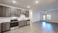Located at 1050 Old Gilliard Rd in Ridgeville, SC, this single-story, 3-bedroom, 3-bathroom home offers a well-designed layout with modern finishes throughout. The open-concept kitchen and living area serves as the heart of the home, where wood-tone cabinetry, granite-style countertops, and a full suite of stainless steel appliances — including a range, microwave, dishwasher, and refrigerator — create a functional and stylish space. Recessed lighting and a ceiling fan enhance the living area, which features wood-look flooring and a glass door that brings in natural light. Each of the three bedrooms is finished with the same durable wood-look flooring, neutral walls, and ceiling fans, offering a clean and versatile canvas. The spacious primary bedroom provides a comfortable retreat. The three bathrooms are appointed with wood-tone vanities, granite-style countertops, large mirrors, and a soaking tub with white tile surround. A dedicated laundry room with a full-size washer and dryer adds everyday convenience. Closets in each bedroom and consistent, contemporary finishes throughout give this home a cohesive and move-in-ready feel.