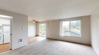 This single-floor, 2-bedroom residence offers a practical and comfortable layout designed to maximize its living space. The open living room is a central highlight, featuring plush wall-to-wall carpeting, a ceiling fan, and a textured ceiling. Large windows flood the room with natural light and provide views of the surrounding neighborhood, while a sliding glass door leads directly to an outdoor deck, seamlessly connecting indoor and outdoor living.

The kitchen and dining areas are positioned adjacent to the living room, with hardwood-style flooring providing a functional transition between spaces, as seen in the 3D floor plan overview.

Both bedrooms are carpeted and offer a calm, neutral ambiance with warm beige tones. The primary bedroom is generously sized, providing ample room for furniture arrangement, and includes a closet with sliding doors. The second bedroom also features a sliding-door closet, a window for natural light, and a baseboard heater for independent climate control.

Throughout the residence, the neutral color palette, consistent flooring choices, and practical storage solutions create a clean, functional living environment suited for everyday comfort.