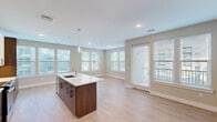 Located at 200 Middletown Blvd in Langhorne, PA, this well-designed 3-bedroom, 2-bathroom residence offers a thoughtful single-floor layout that maximizes both functionality and comfort. The open-concept kitchen and living area serves as the heart of the home, anchored by a large center island with a white quartz countertop, undermount sink, and elegant pendant lighting. The kitchen features rich dark wood cabinetry paired with crisp white upper cabinets, a subway tile backsplash, and stainless steel appliances. Light hardwood flooring flows throughout the main living areas, complemented by neutral warm-toned walls and an abundance of natural light streaming through multiple windows fitted with horizontal blinds. The living area is generously proportioned with views to the outdoors. Each of the three bedrooms is carpeted and finished with the same soft neutral palette, offering a calm and restful atmosphere. The primary bedroom is a comfortable size with ample room for furnishings. The two bathrooms are clean and modern — one features a soaking tub with full tile surround and curved shower rod, while the second includes a long wood vanity with white countertop and a large mirror. The overall ambiance is contemporary, bright, and move-in ready.