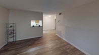 This single-floor residence offers a functional and comfortable layout designed to maximize everyday living. The living room serves as a welcoming entry point, featuring rich, dark wood-look flooring, neutral-toned walls, and a large window that fills the space with natural light. A pass-through window connects the living area to the kitchen, creating an open, communicative flow between the two spaces.

The galley-style kitchen is efficiently designed with white cabinetry, granite-look countertops on both sides, and wood-look flooring that extends through the adjacent hallway. The layout provides ample counter space and storage, making it a practical workspace.

The bedrooms are carpeted in warm, neutral tones and each feature windows with blinds that allow for natural light and privacy. One bedroom stands out with access to a spacious walk-in closet outfitted with built-in shelving and hanging rods, as well as a connected bathroom.

The bathroom is well-appointed with a wide vanity featuring granite-style countertops, a large mirror with overhead lighting, white cabinetry, wood-look tile flooring, and a tub-shower combination. The overall design throughout the residence is clean, neutral, and move-in ready, offering a comfortable and practical living environment.