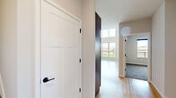 Located at 8421 Mansion Hill Ave, this two-floor residence offers a well-designed layout across a spacious main level and a comfortable upper level. The main floor is generously proportioned, anchored by an open living area with striking double-height ceilings that create an airy, expansive atmosphere. Light hardwood flooring flows throughout, complementing the clean, neutral palette of the walls. The modern kitchen features a peninsula with a built-in sink, dark cabinetry, stainless steel appliances—including a refrigerator, microwave, and range—and recessed lighting, making it both functional and stylish. A dedicated laundry area with a full-size washer and dryer provides added convenience, situated adjacent to the full bathroom, which is finished with light hardwood flooring and clean, simple fixtures. A staircase leads to the upper level, where the private bedroom offers plush carpeting, a ceiling fan, a wall-mounted mini-split HVAC unit for personalized climate control, and a window with a balcony view overlooking open green fields. A closet and hallway complete the upper floor. Throughout the home, abundant natural light, scenic outdoor views, and thoughtful finishes come together to create a bright, comfortable living environment.
