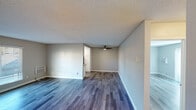 Located at 5810 Amaya Dr in La Mesa, California, this single-floor unit offers a clean, modern aesthetic throughout. The open living area is finished with stylish wood-look plank flooring in cool gray tones, neutral gray walls, and a textured ceiling. A ceiling fan adds practicality, while a sliding glass door fitted with vertical blinds fills the space with natural light and provides views of the surrounding neighborhood and palm trees.

The kitchen stands out with crisp white cabinetry, granite-style countertops, and a full suite of stainless steel appliances including an electric range, over-the-range microwave, dishwasher, and refrigerator. A window above the double sink lets in additional natural light, making the kitchen bright and functional.

The bedrooms carry the same warm wood-look flooring and neutral palette, with ceiling fans and windows providing ventilation and light. One bedroom features a spacious walk-in closet with dual shelving rods on both sides, offering generous storage. The bathroom is well-appointed with a full soaking tub and shower combo, accented by a curved curtain rod and chrome fixtures. Throughout the unit, clean white baseboards and a consistent neutral color scheme create a cohesive, move-in-ready environment.