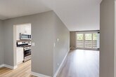 Located at 1910 Chestnut Ave in Glenview, IL, this well-appointed single-floor, 3-bedroom, 2-bathroom home offers a thoughtfully designed layout with modern finishes throughout. Light hardwood-style flooring runs through the main living areas, complementing the neutral taupe and gray color palette. The living room features vaulted ceilings and a large sliding glass door that floods the space with natural light and provides views of the surrounding greenery. Adjacent to the living area, the kitchen is a standout feature with white shaker cabinetry, quartz countertops, a gray subway tile backsplash, open wood shelving, and a full suite of stainless steel appliances. A dedicated dining room and convenient in-unit laundry complete the communal spaces. The spacious primary bedroom offers direct access to a beautifully finished en-suite bathroom, featuring a dual-sink vanity with white cabinetry, quartz countertops, and backlit mirrors. The secondary bedrooms are comfortably sized, carpeted, and each equipped with a ceiling fan and natural light from window treatments. The second bathroom maintains the same clean, modern aesthetic with light wood flooring and white vanity finishes. Four closets provide ample storage throughout the home.