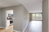 Located at 1910 Chestnut Ave in Glenview, IL, this well-appointed single-floor, 3-bedroom, 2-bathroom home offers a thoughtfully designed layout with modern finishes throughout. Light hardwood-style flooring runs through the main living areas, complementing the neutral taupe and gray color palette. The living room features vaulted ceilings and a large sliding glass door that floods the space with natural light and provides views of the surrounding greenery. Adjacent to the living area, the kitchen is a standout feature with white shaker cabinetry, quartz countertops, a gray subway tile backsplash, open wood shelving, and a full suite of stainless steel appliances. A dedicated dining room and convenient in-unit laundry complete the communal spaces. The spacious primary bedroom offers direct access to a beautifully finished en-suite bathroom, featuring a dual-sink vanity with white cabinetry, quartz countertops, and backlit mirrors. The secondary bedrooms are comfortably sized, carpeted, and each equipped with a ceiling fan and natural light from window treatments. The second bathroom maintains the same clean, modern aesthetic with light wood flooring and white vanity finishes. Four closets provide ample storage throughout the home.