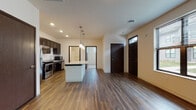 Located at 2800 Clausen St in Fitchburg, Wisconsin, this single-floor unit offers a thoughtfully designed layout with modern finishes throughout. The open-concept living and kitchen area serves as the heart of the space, anchored by a central island topped with granite countertops and illuminated by elegant pendant lighting. The kitchen is equipped with a full suite of stainless steel appliances, including a refrigerator, range, microwave, and dishwasher, all complemented by rich, dark cabinetry that extends to the ceiling for ample storage. Recessed lighting and durable hardwood-style flooring flow throughout the main living area, creating a warm and cohesive aesthetic. The spacious living area offers generous room for furnishings and benefits from natural light streaming in through large windows. The bedroom features plush carpeting and multiple windows fitted with blinds, providing a comfortable and well-lit retreat. The bathroom is clean and functional, with light tile flooring, a combination tub and shower, and a vanity with a countertop sink. Dark-framed interior doors and trim provide a striking contrast against the neutral wall tones, lending the space a contemporary and polished character throughout.